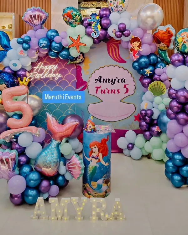 My complete underwater fantasy with a 'Little Mermaid' theme for Amyra's 5th birthday. This setup features a custom backdrop, an elaborate balloon arch in ocean colors, character standees, themed props, and light-up marquee letters for the name.