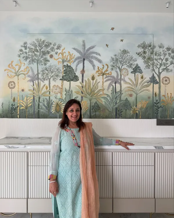 Art has the power to completely transform a room. My mother, Hansa Sewani, stands beside the 3D wall mural she created for this dining area. It took over 150 hours of handwork, using ceramic paste, acrylics, and gold leaf to bring this magical, nature-inspired scene to life.