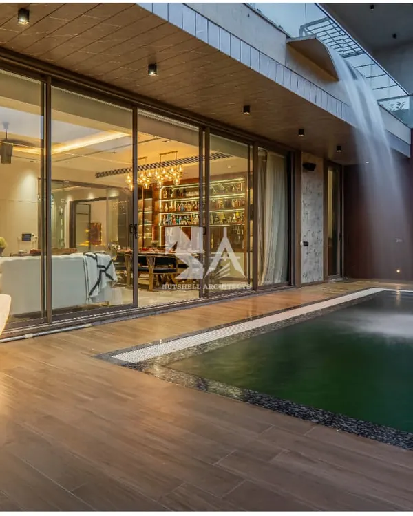 This poolside deck, crafted from warm wood, provides a seamless transition from the indoor living area to the outdoor oasis. A sculptural, moon-shaped lamp adds a touch of artistry and provides gentle illumination for evening gatherings.