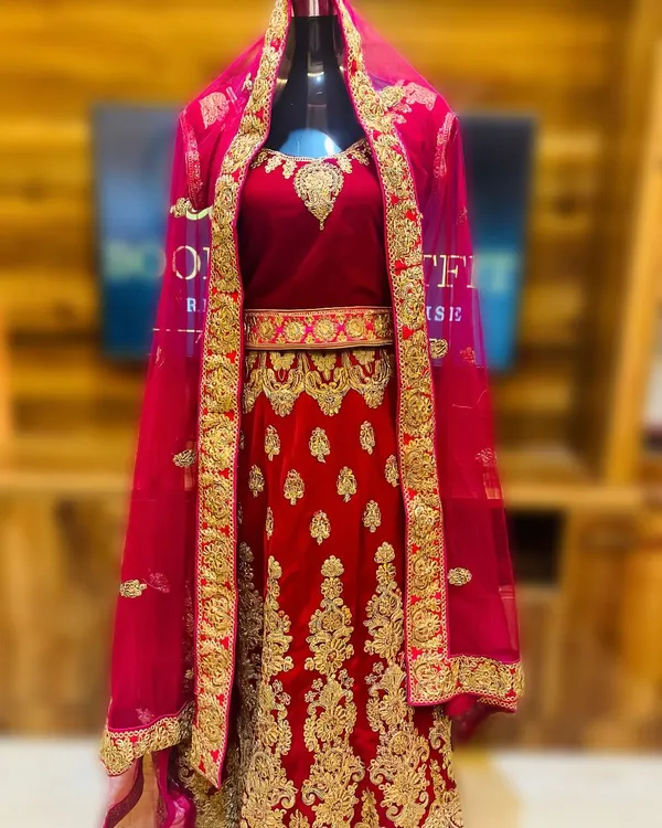 This is my classic red velvet bridal lehenga, available for rent. It features extensive gold embroidery across the skirt and blouse, making it a perfect statement piece for a traditional wedding ceremony.