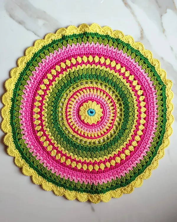 This is the beautiful Viola mandala, a free pattern I found and loved making. I used knitting cotton and a 3.5mm hook to create this vibrant piece with rings of pink, green, and yellow.
