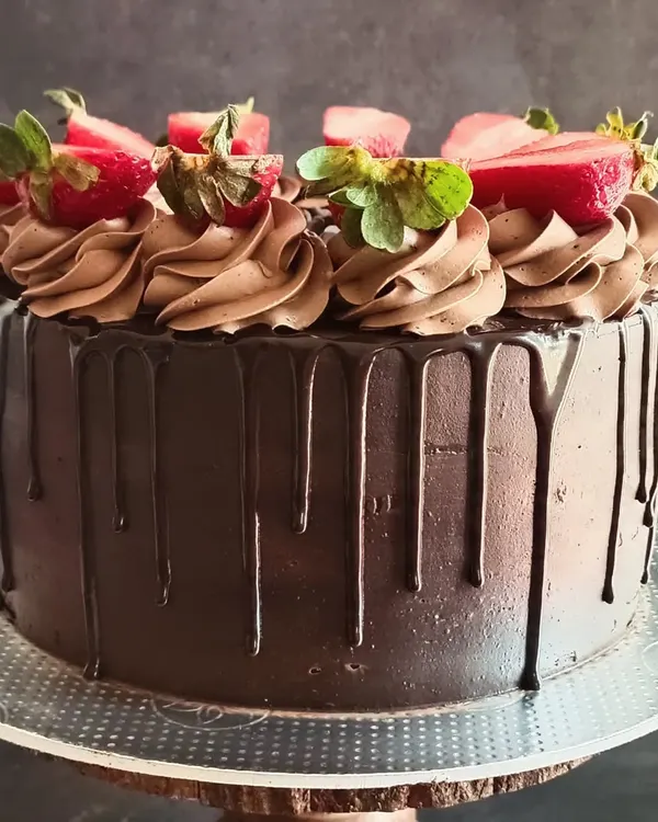 My Death by Chocolate cake is a crowd-pleaser, featuring a moist chocolate sponge, rich chocolate frosting, and a glossy ganache drip. It's topped with fresh strawberries for a perfect flavor combination.