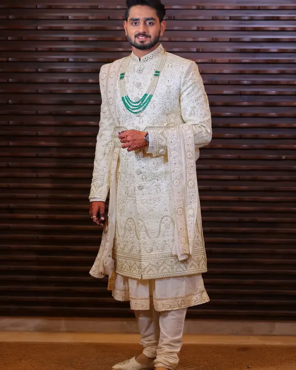 This is a complete groom's look I designed. It features a cream sherwani in a computerized fabric with intricate katdana work, layered over an anarkali kurta and chudidar, and styled with a matching dupatta and mojari shoes.
