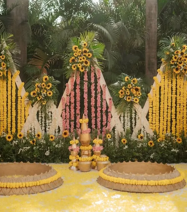 This is a complete Haldi setup I designed, featuring a backdrop of marigold and sunflower curtains, traditional brass pots (matkas), and seating areas for the bride and groom, all tied together with a carpet of yellow petals.