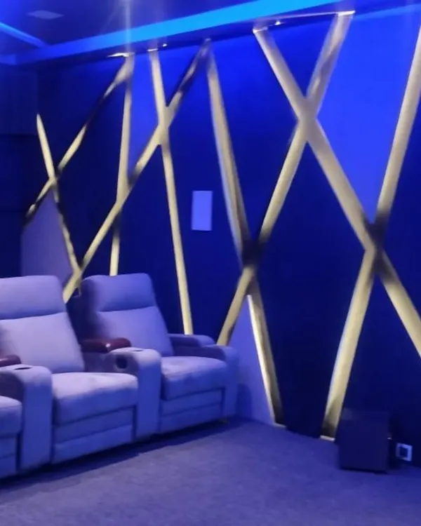 A closer look at a custom acoustic wall featuring a geometric, backlit design. This not only enhances the room's modern aesthetic with vibrant blue light but also helps in managing sound reflections.