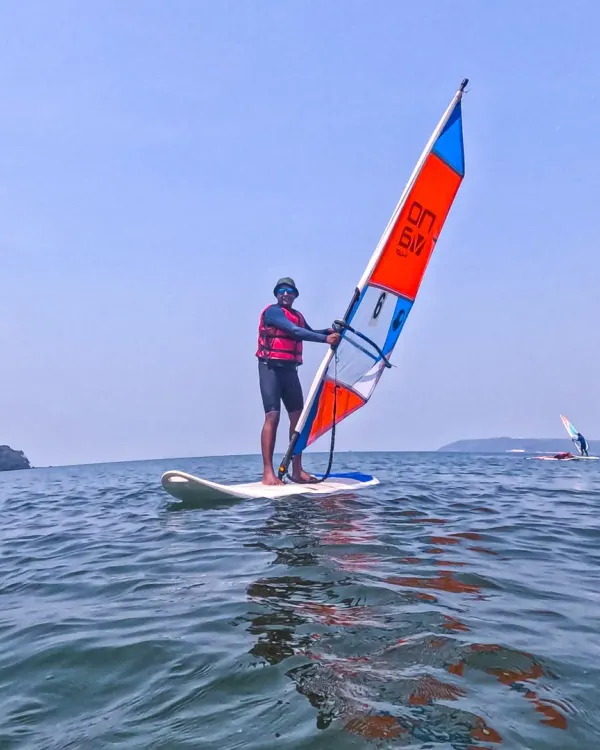 A windsurfer expertly balances on his board, harnessing the power of the wind to glide across the sea in Goa. We provide all the necessary gear and instruction for you to learn this graceful and challenging sport.