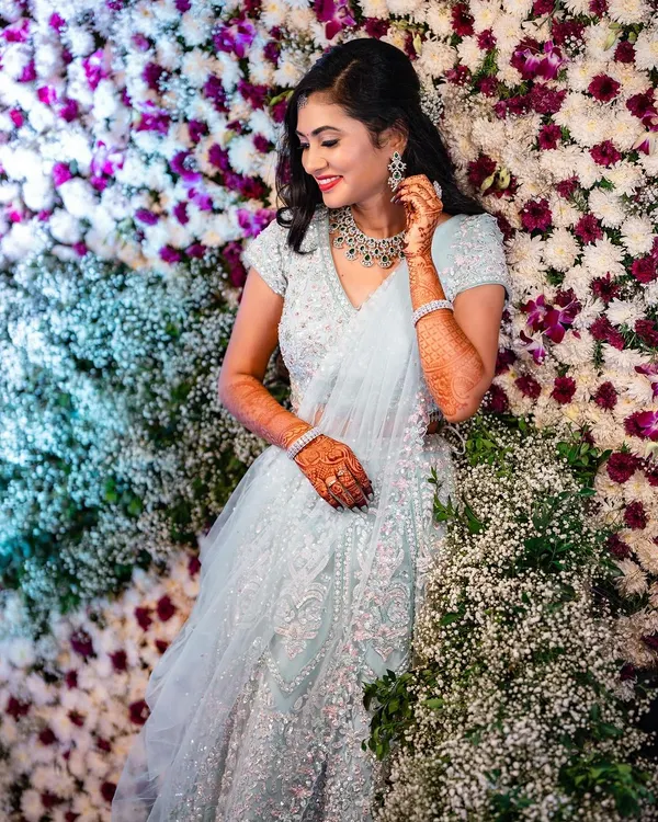 A fairytale moment for this beauty in her shimmering lehenga. Set against a wall of flowers, her soft glam makeup with a bright smile makes for a perfect reception photo.