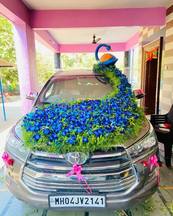 This is my signature peacock themed wedding car decoration on a Toyota Innova. The design features a beautiful peacock figure with a long, flowing tail of blue orchids and greenery covering the bonnet, making it a true showstopper.