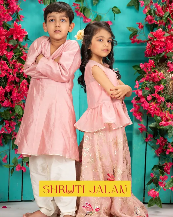 This pastel pink sibling set is one of my most popular designs for Rakhi and family photoshoots. The boy's simple angrakha style kurta perfectly complements the girl's peplum top and printed lehenga skirt, creating a look of effortless charm.