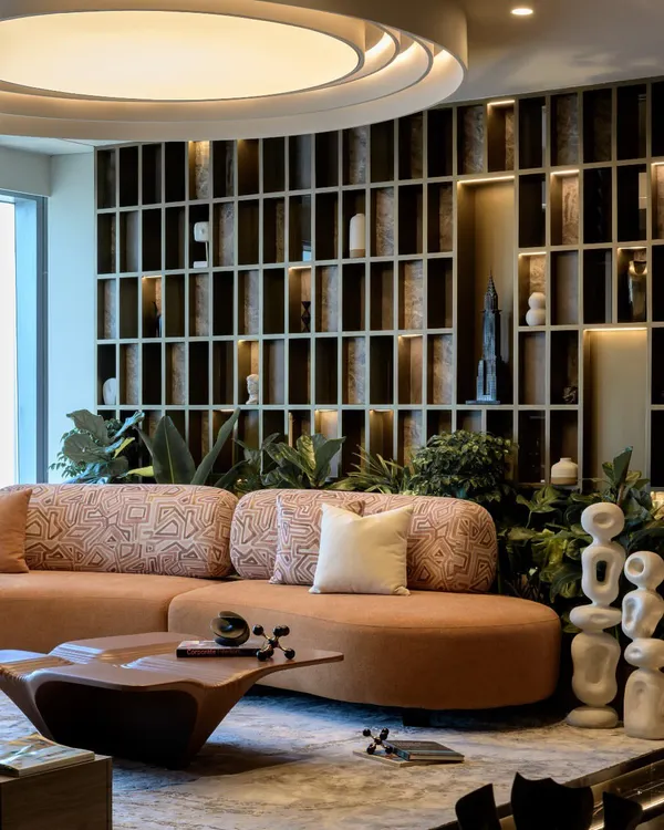 A wide view of the Midas Lounge, showing the harmony between the custom jacquard sofa, the backlit grid wall, and the abundant greenery. This space is designed for conversation and connection.