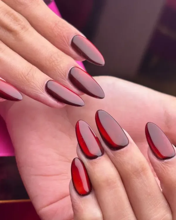 A bold and trendy look featuring deep red "jelly" nails. This translucent, glossy finish on almond-shaped extensions is a modern style that makes a vibrant and fashionable statement.