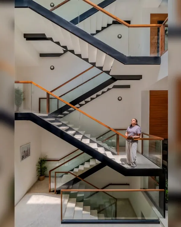 This staircase is the spine of the villa, connecting three floors with an exposed metal frame and cantilevered landings. We designed it not just for circulation, but as a moving gallery that offers ever-changing views of a custom 'Tree of Life' metal artwork, turning a simple journey through the home into an experience.