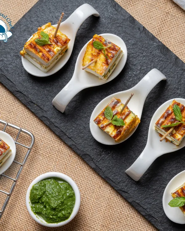 These Rozali Stuffed Paneer Sandwiches are a unique twist on a classic. Layers of paneer and flavorful stuffing are grilled and served in elegant bite-sized portions on ceramic spoons, making them a perfect mess-free option for any corporate gathering.