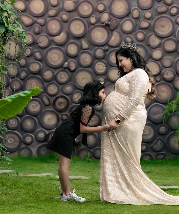 A big sister whispers secrets to her sibling on the way. This outdoor maternity photo captures the beautiful bond between a mother, her daughter, and the new life they are waiting for.