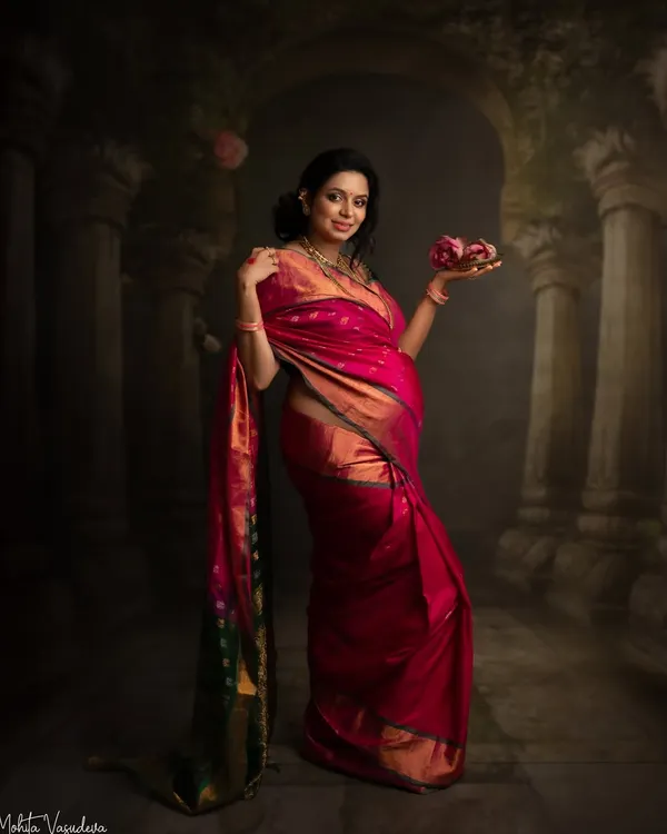 This portrait feels like a painting. The rich color of the silk saree, the artistic backdrop, and the traditional elements come together to create a truly timeless piece of art.