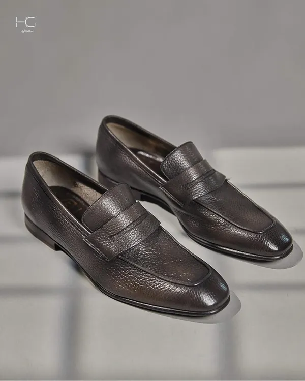 Crafted for the luxury man, these dark brown textured leather loafers are a testament to timeless style and quality. The classic penny loafer design is elevated by the rich, grained leather.