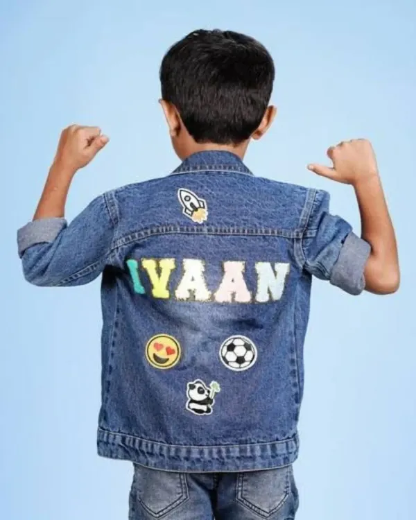 A custom denim jacket for a boy named "Iyaan," decorated with patches of a rocket, emoji, soccer ball, and panda.
