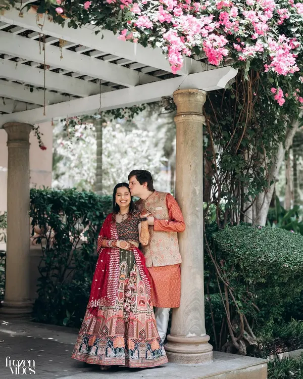 A sweet, candid moment between Shubhi and Devan under a canopy of pink bougainvillea at the ITC Maratha. The natural frame created by the flowers adds a soft, romantic touch.