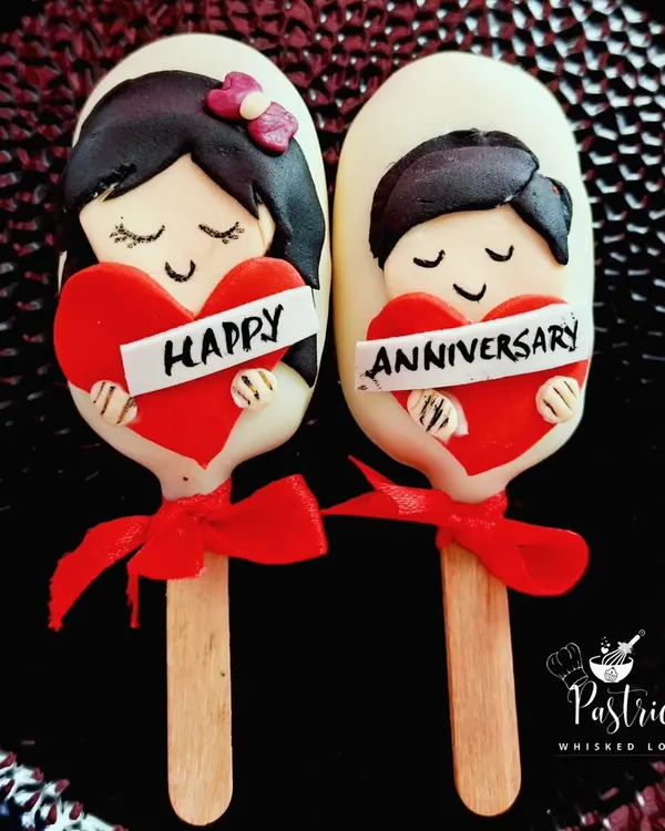 These adorable, customized cakesicles were made for an anniversary. They are filled with dark chocolate cake and decorated with hand-modeled fondant to celebrate the couple.