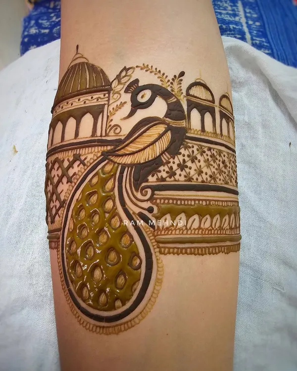 A detailed peacock arm band with a palace dome background. This is a classic and royal design, perfect for bridal or festive wear.