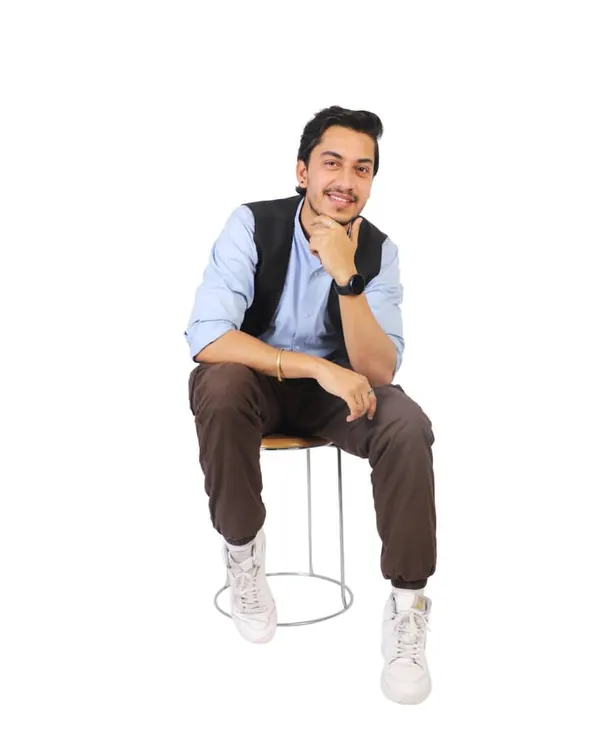 A professional portfolio headshot for a male model, seated and smiling. These clean, well-lit shots are essential for casting calls and profiles.