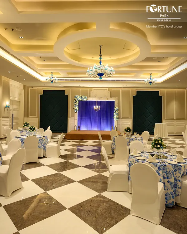 This is my premier banquet hall, elegantly decorated for a grand celebration. The striking blue and white floral tablecloths, combined with crystal chandeliers and a polished marble floor, create a sophisticated atmosphere for weddings and formal receptions.