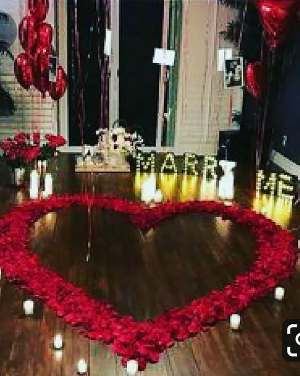 This is the ultimate romantic gesture for a proposal. I create a large, beautiful heart on the floor using hundreds of rose petals, surrounded by the warm glow of candles and illuminated "MARRY ME" letters for a truly breathtaking moment.