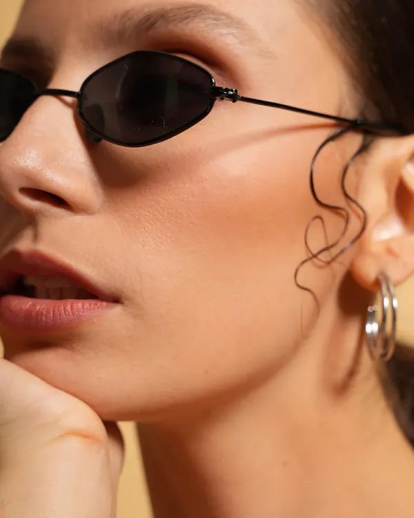 A clean and modern beauty shot focusing on the chic sunglasses and subtle wet-look hair styling. This type of close-up is perfect for accessory brands or minimalist beauty campaigns.