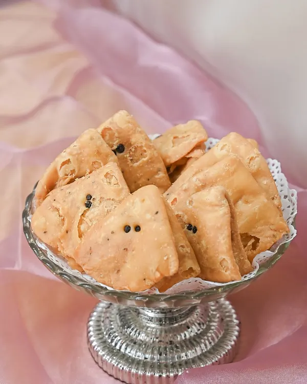I am passionate about keeping traditions alive. This is a bowl of my golden, crispy mathis, a classic savory snack that is an essential part of my traditional wedding bhaji packs.