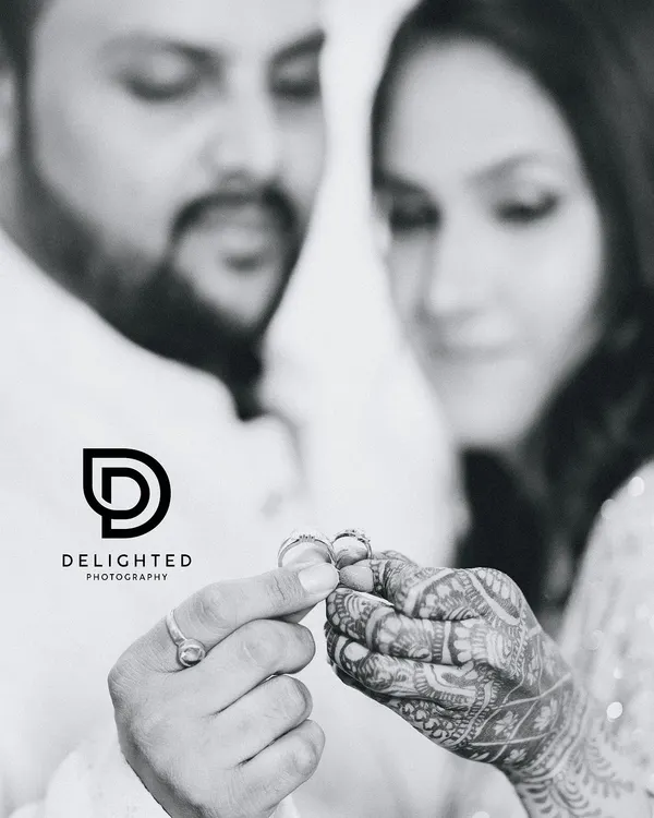 A symbolic black and white shot focusing on the couple's hands as they hold their wedding rings, representing their new commitment and union.