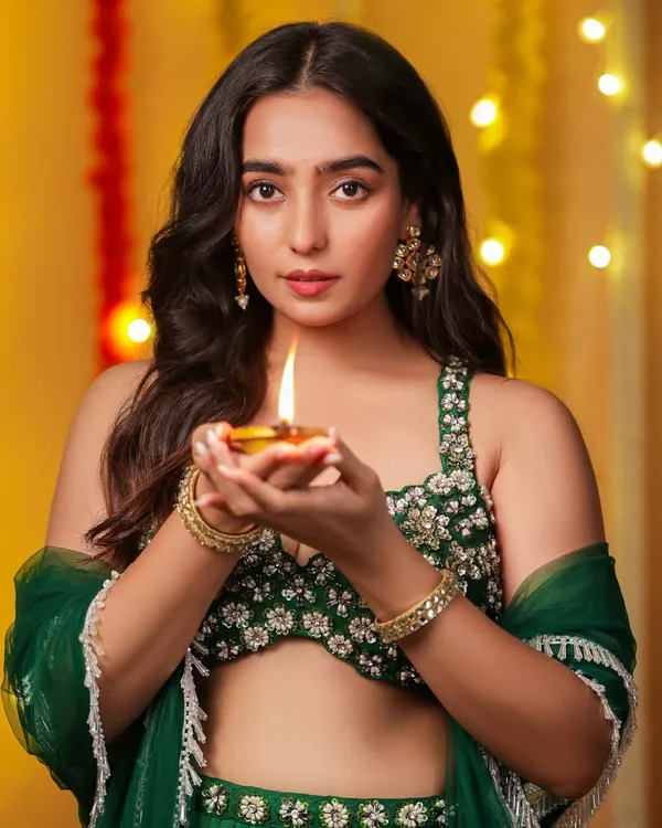 A radiant Diwali-themed portrait. The model holds a lit diya, and the warm glow illuminates her face, perfectly capturing the spirit of the festival of lights.