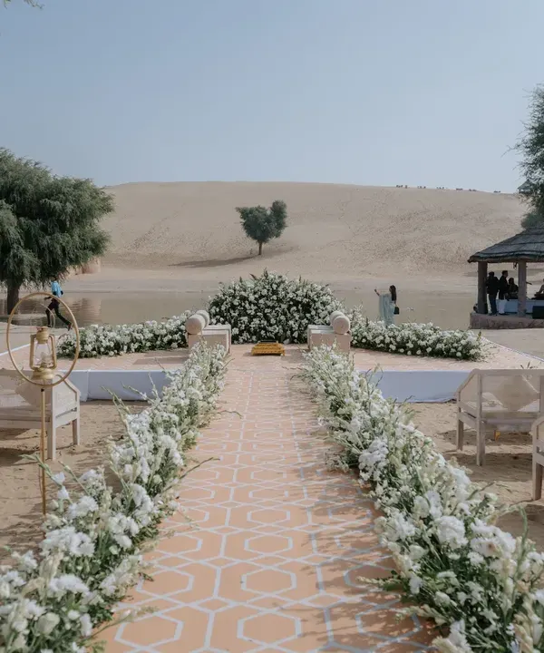A pristine white floral aisle set against the vast expanse of the Rajasthan sand dunes, creating a truly one-of-a-kind mandap for a desert wedding.