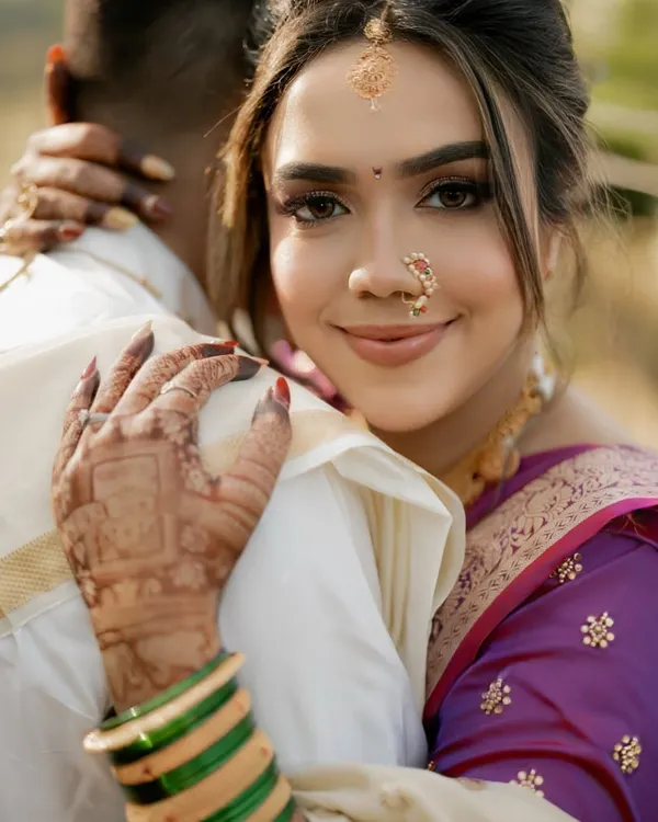 A close-up of our stunning Marathi bride. The look features subtle makeup, the traditional crescent bindi, a classic nath, and other accessories that celebrate her Maharashtrian heritage.