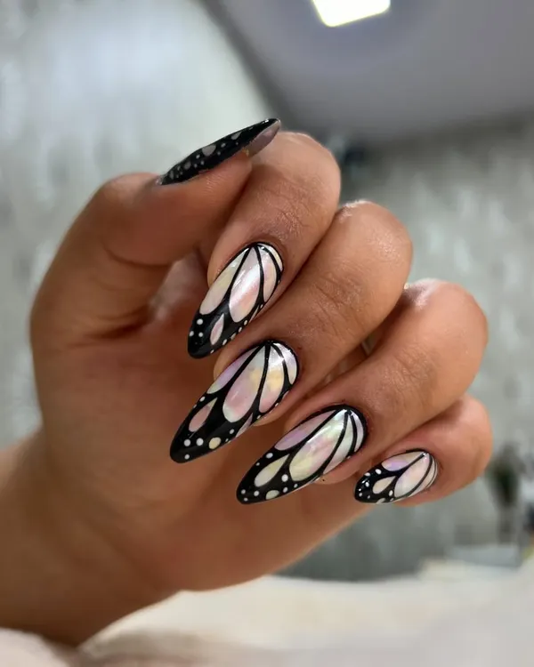 A side view of the popular iridescent butterfly wing nails, showing how the design wraps around the curve of the long stiletto extension.