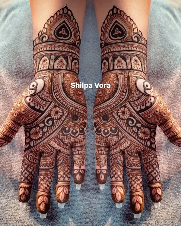 A perfectly symmetrical bridal design with heavy, detailed work covering the entire hand. The use of negative space makes the patterns pop.
