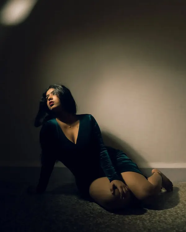 A dramatic portrait using a single, focused light source to create a spotlight effect. The deep shadows and rich color grading give this shot a cinematic, mysterious quality.