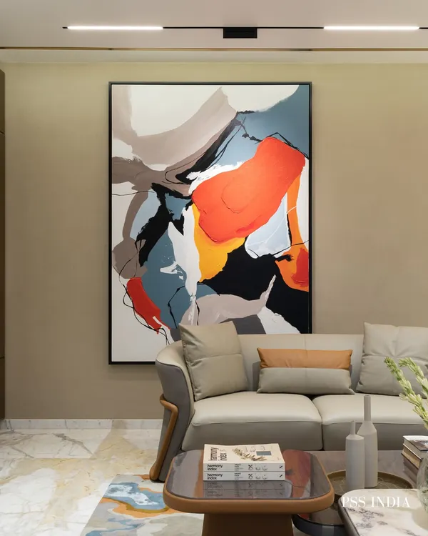 The power of abstract art. This large, dynamic painting with its bold strokes of orange, blue, and black becomes the immediate focal point of the living room, adding energy and movement to the neutral space.