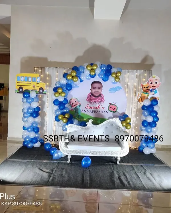 A fun Cocomelon theme for an Annaprasan ceremony. This setup includes a custom backdrop with the baby's photo, character cutouts on balloon pillars, and a small white throne for the main event.