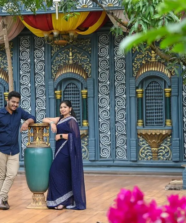 This couple chose a South Indian village theme for their pre-wedding shoot. The intricate blue wall and traditional elements create a stunning backdrop.