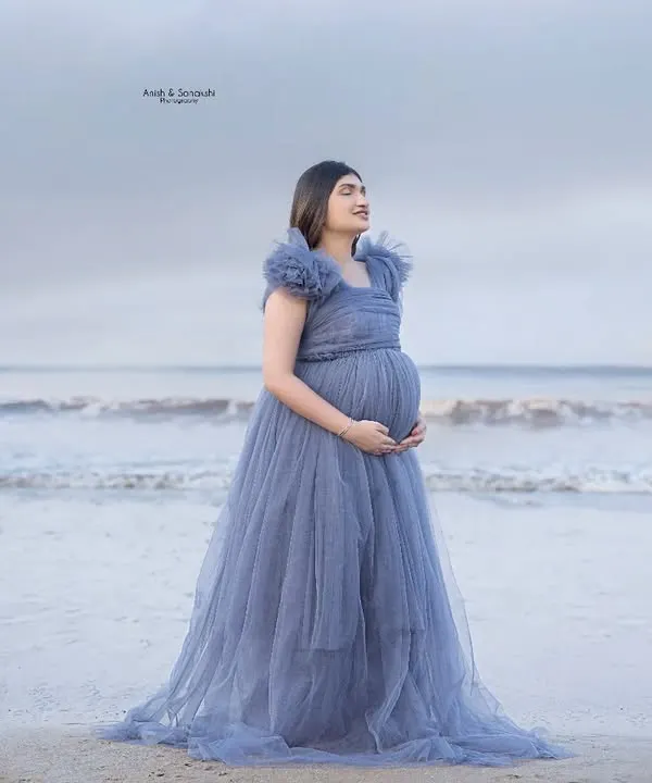 A little piece of heaven by the sea. This mama-to-be looks absolutely ethereal in a dusty blue tulle gown, standing by the calm ocean. It's a perfect, serene beach maternity portrait.