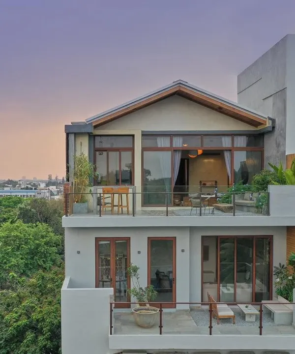 The exterior of the Magnolia Residence, a duplex penthouse in Bangalore. The design features a pitched roof and extensive balconies, creating a house-like feel in the sky with ample space for outdoor living.
