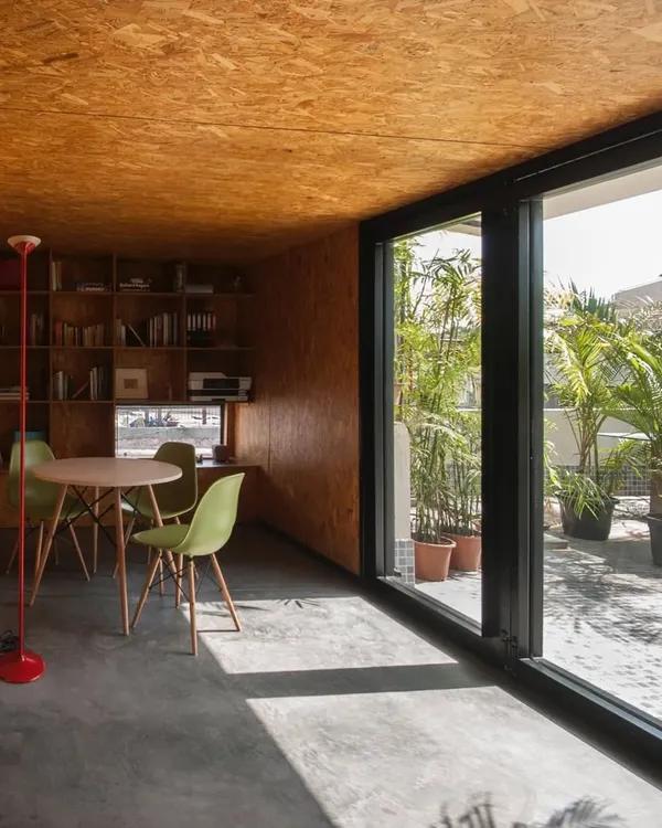 A small workspace we designed for a journalist, seen from the terrace. The use of OSB wood for all interior surfaces creates a warm, monolithic feel, while the large glass opening connects the office to the outdoors.