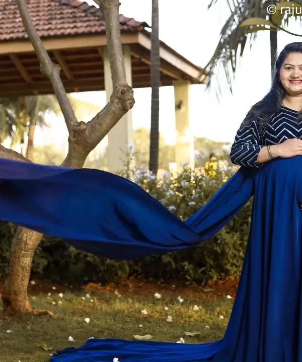 A flowing gown adds such a magical element to an outdoor maternity shoot. Here, the deep blue fabric contrasts beautifully with the natural greenery, creating an elegant and striking portrait of the mom-to-be.