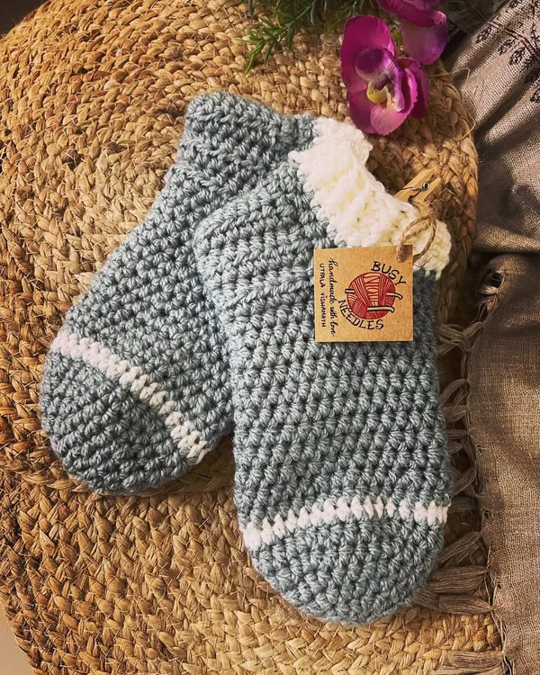 Keep your feet warm and cozy with these handmade crochet socks. This pair in grey and white is perfect for lounging at home on a cold night.