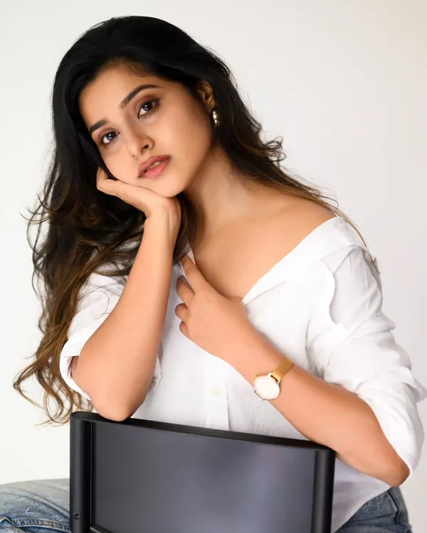 A classic, clean studio portrait with a white shirt and jeans. The bright, even lighting and simple background put all the focus on the subject's natural beauty and expression.