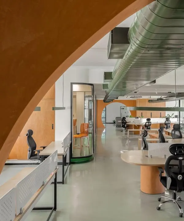 An arched entryway frames the view into the open-plan office we designed for Hosachiguru. The color palette of terracotta and forest green, along with exposed ducting, reflects the company's focus on sustainable farming and technology.