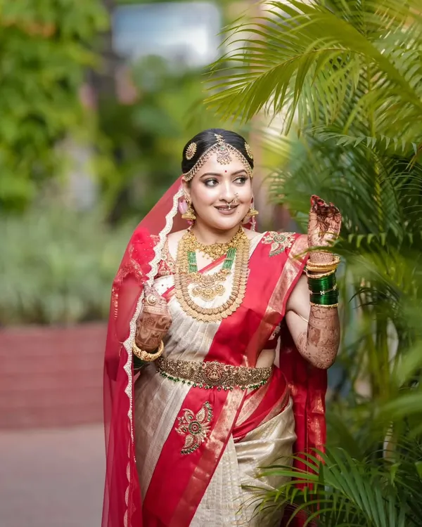 We believe a wedding saree is a timeless treasure. Here is one of our beautiful brides, Anjana, looking radiant in a custom-curated red and white Kanjivaram, a piece that perfectly complements her joyous celebration.