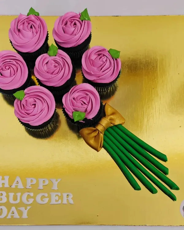 Why give flowers when you can give a cupcake bouquet? This creative arrangement features six chocolate cupcakes piped with pink frosting to look like roses, all presented on a golden board.