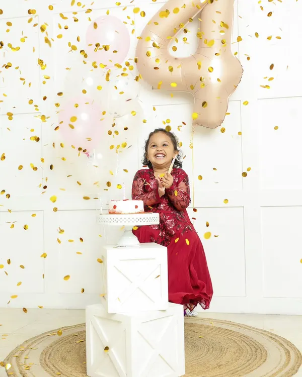 Pure birthday joy. This little girl is showered in golden confetti as she celebrates turning four, her happy laugh lighting up the room.