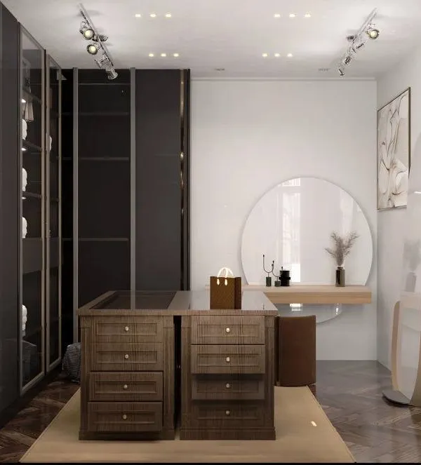 A spacious walk-in closet featuring dark, sleek wardrobes and a central island with drawers for accessories. The large round mirror and separate vanity area create a dedicated and luxurious dressing space.